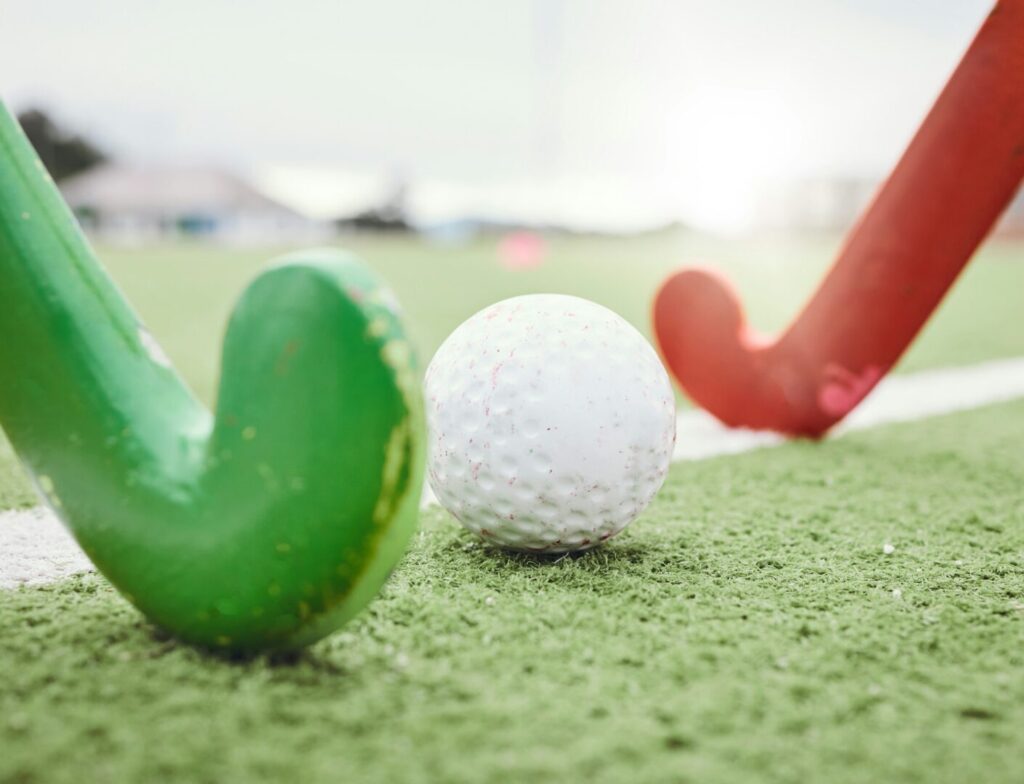 Hockey, game and stick with ball on green, field or pitch with sports equipment in competition, mat